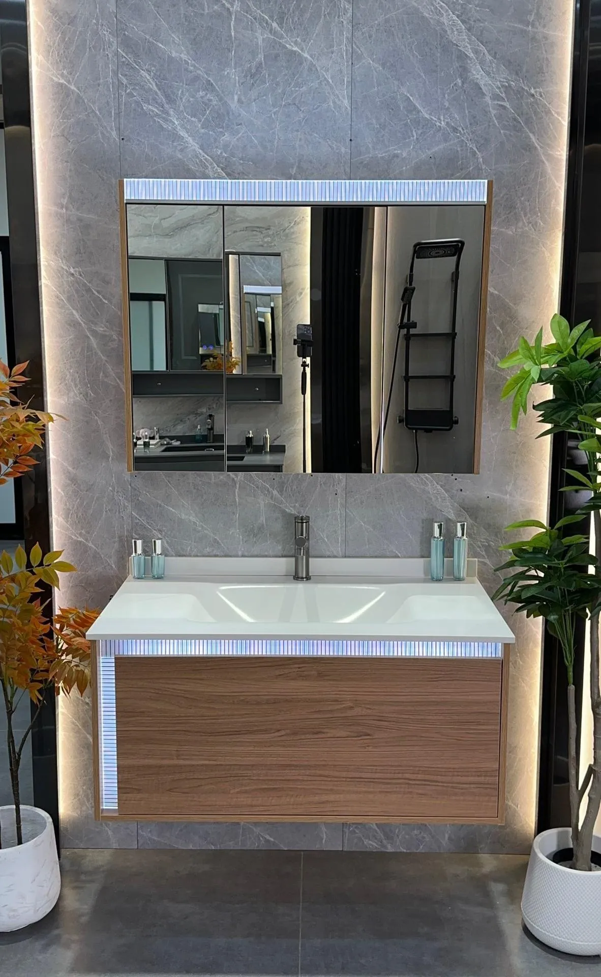 Aria 100 vanity: wide single sintered stone basin in a soft walnut grain, formed in one piece on a wall-hung cabinet.
