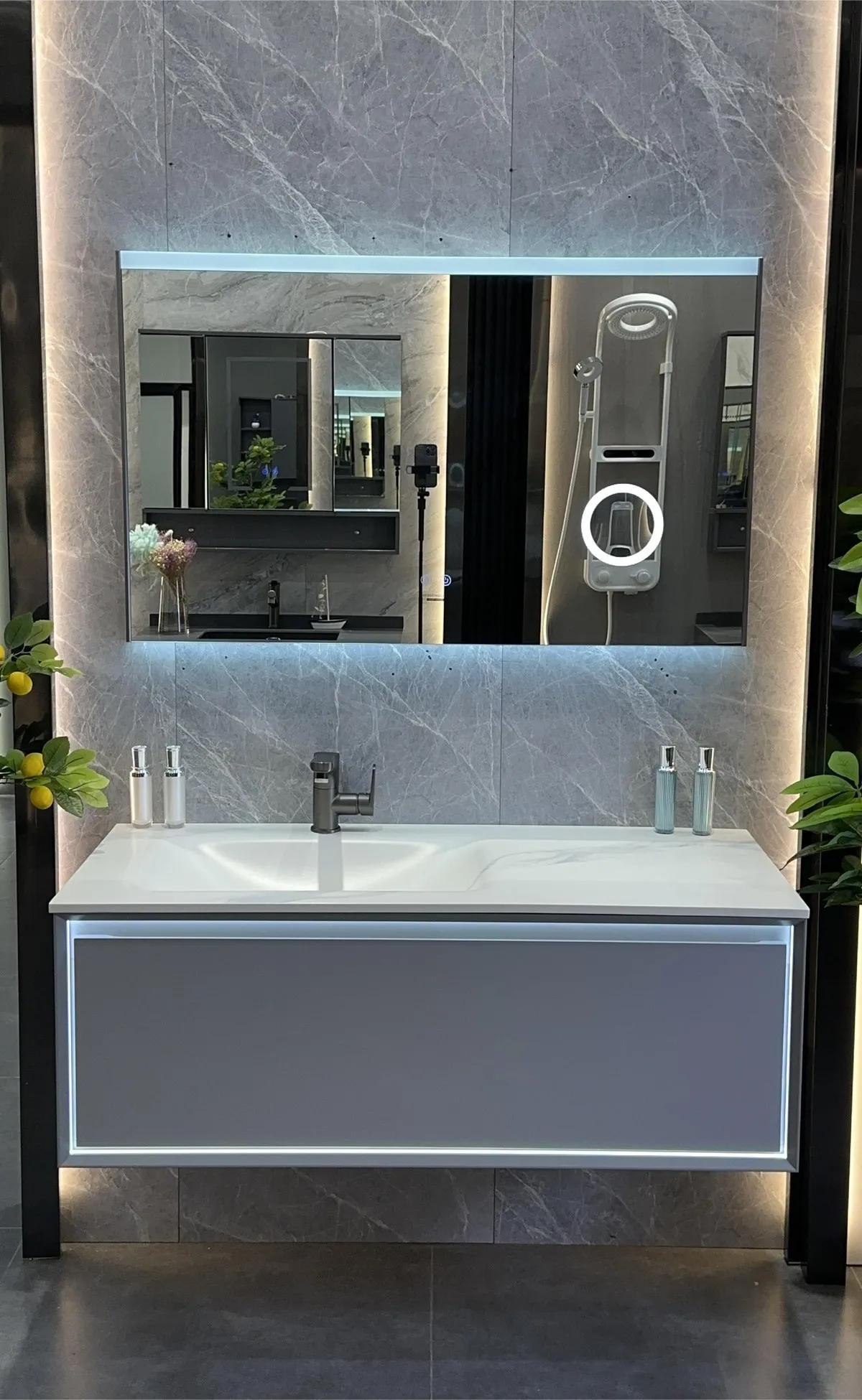 Hot-bent sintered stone basin vanity with seamless white basin, wall-hung grey cabinet and full-width LED smart mirror, on display in the Vora Surfaces showroom.